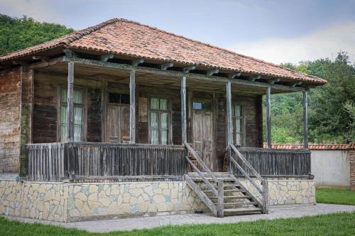 an old house with a wooden porch and a staircase at Ethno Sazano Hotel in Sazano