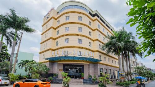 een oranje auto geparkeerd voor een geel gebouw bij Tahami Hotel Thu Duc in Ho Chi Minh-stad