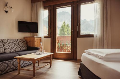 pokój hotelowy z łóżkiem, kanapą i stołem w obiekcie Kristallhotel Corona-Krone w mieście San Vigilio di Marebbe