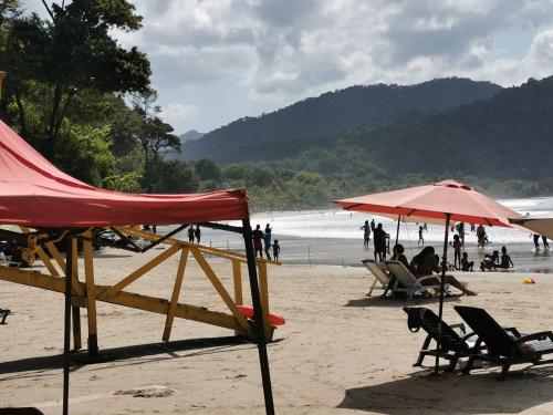 een strand met stoelen en parasols en mensen op het strand bij Karibik Trinidad Ocean few guesthouse in Las Cuevas