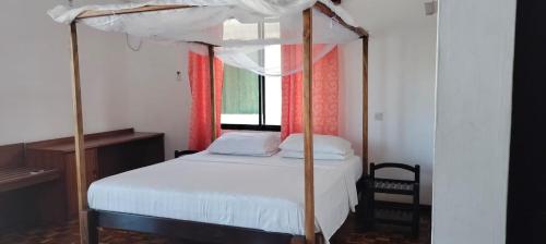 een slaapkamer met een hemelbed bij Comfy 1bedroom in Ukunda