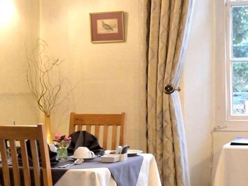 a dining room table with a white table cloth on it at Sonata Guest House in Kendal