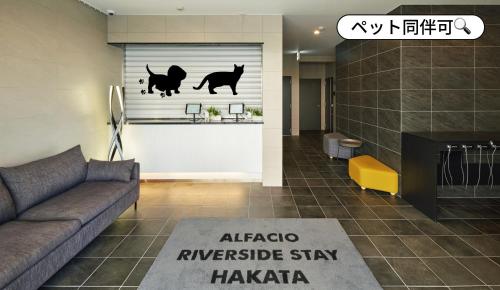a living room with a couch and a window with cats on it at ALFACIO RIVERSIDE STAY HAKATA in Fukuoka