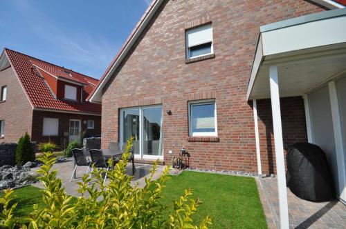uma casa de tijolos com um pátio e um quintal em Nr 135 - Ferienhaus "Wattfieber" In't Seeburger Winkel em Carolinensiel