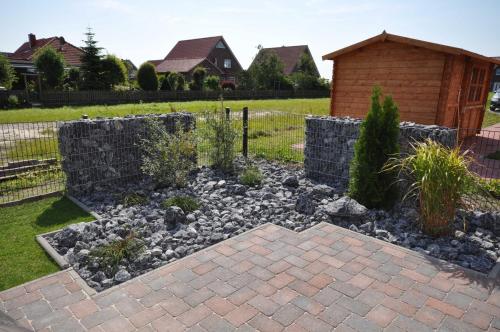 um jardim com pedras e uma parede de retenção em Nr 135 - Ferienhaus "Wattfieber" In't Seeburger Winkel em Carolinensiel