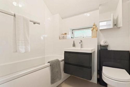 a white bathroom with a sink and a toilet at Snug & Cosy Home In Thamesmead Overlooking A Park in Thamesmead