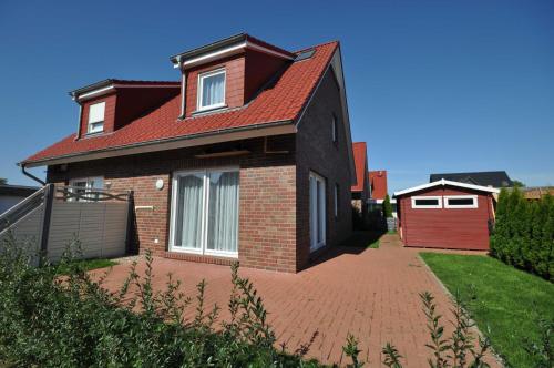 una casa con techo rojo y entrada de ladrillo en Nr 137 - Ferienhaus In't Seeburger Winkel, en Carolinensiel