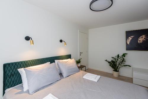 Schlafzimmer mit einem Bett mit einem grünen Kopfteil in der Unterkunft Žalioji smilga in Palanga