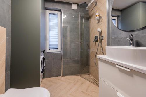 ein Badezimmer mit Dusche, Waschbecken und Spiegel in der Unterkunft Žalioji smilga in Palanga