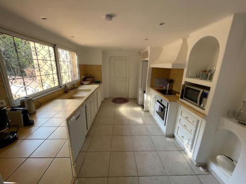 Il comprend une grande cuisine avec des placards blancs et du carrelage. dans l'établissement Villa Bianca - Vue imprenable Mer & Porto-Vecchio, Piscine chauffée à débordement, Accès privé plage, à Porto-Vecchio