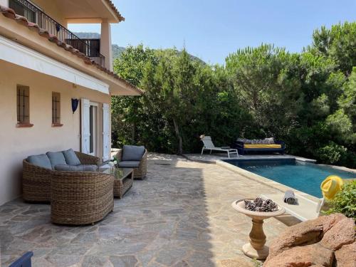 d'une terrasse avec des meubles en osier à côté d'une piscine. dans l'établissement Villa Bianca - Vue imprenable Mer & Porto-Vecchio, Piscine chauffée à débordement, Accès privé plage, à Porto-Vecchio