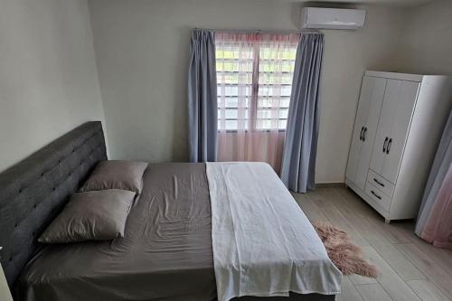 a bedroom with a bed and a dresser and a window at Paradijs in Paramaribo in Paramaribo
