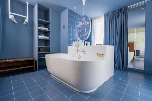 Baño azul con bañera blanca y azulejos azules en The Ruck Hotel, en Lyon