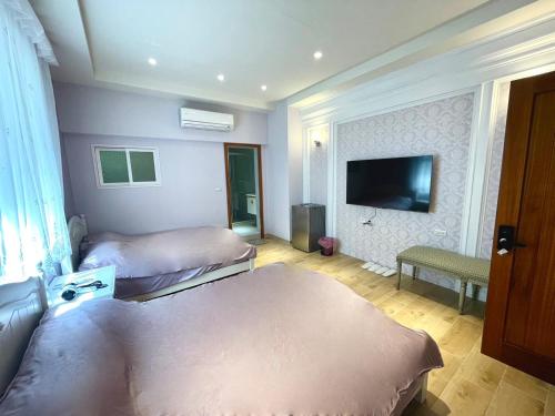 a room with two beds and a flat screen tv at 寶格儷舍 in Tainan