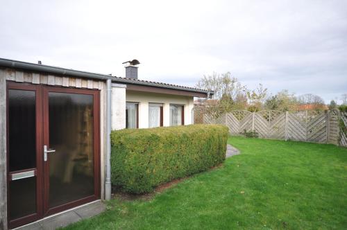 a house with a large glass door in a yard at Nr 201 - Ferienhaus Am Tief in Neuharlingersiel