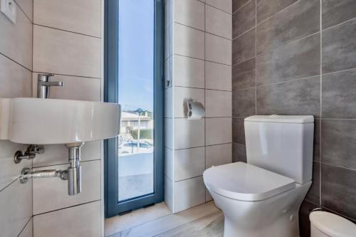 a bathroom with a toilet and a sink and a window at Villa Sonata in Ingrina Sol in Raposeira