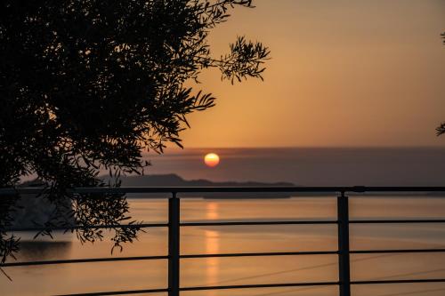 a sunset over a body of water with a fence at Thesan Villas in Marathias