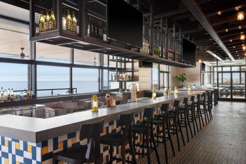 a bar in a restaurant with chairs and windows at Delta Hotels by Marriott™ Virginia Beach Waterfront Suites in Virginia Beach