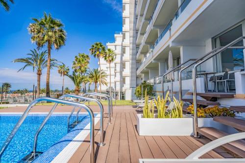 a balcony with a swimming pool and palm trees at Coral Ocean View - Adults Only in Playa de las Americas