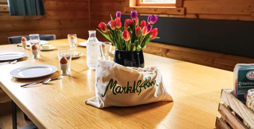 a wooden table with a vase of flowers on it at MarktlAlm - Superior Waldblick Chalet mit Sauna in Turracher Hohe