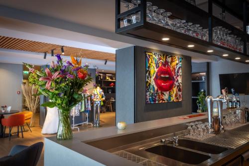 a kitchen with a sink with a vase of flowers at ibis Styles Den Haag Scheveningen in Scheveningen
