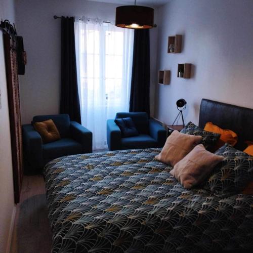 um quarto com uma cama e duas cadeiras azuis em Les chambres du vieux quartier em Thouars