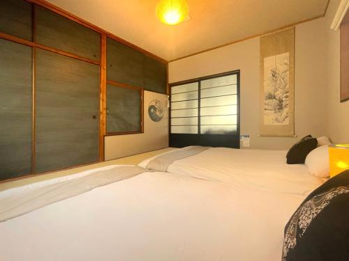 a bedroom with two white beds and a window at guesthouse築港 in Osaka