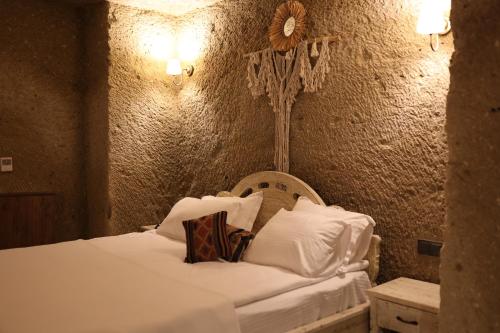 a bedroom with a bed with white sheets and pillows at Cappadocia Vita Cave Hotel in Urgup