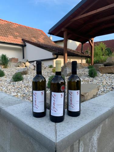 three bottles of wine sitting on a stone wall at Vinný sklep S&T Výmola in Mikulčice