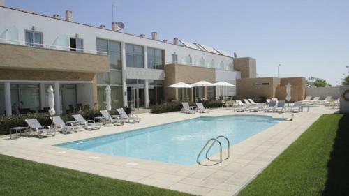 a swimming pool in front of a hotel with chairs and a building at Hotel A Esteva in Castro Verde