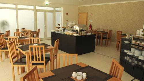a restaurant with wooden tables and chairs and a kitchen at Hotel A Esteva in Castro Verde