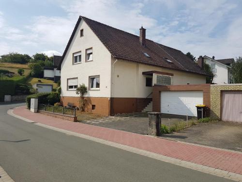 a white house with a garage on the side of a street at Freizimmer in Aßlar Klein-Altenstädten 