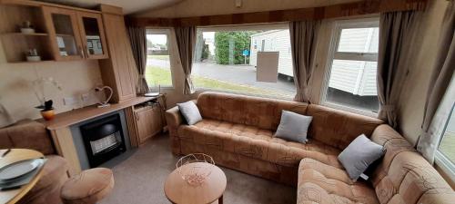 a living room with a couch and a fireplace at Brilliant 6 Berth Caravan At Dovercourt Holiday Park Ref 44009a in Great Oakley
