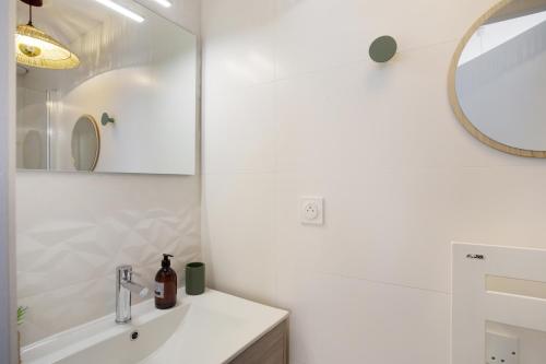 La salle de bains est pourvue d'un lavabo et d'un miroir. dans l'établissement L'Air - Elégant 2 chambres avec loggia dans résidence de haut standing, à Rennes