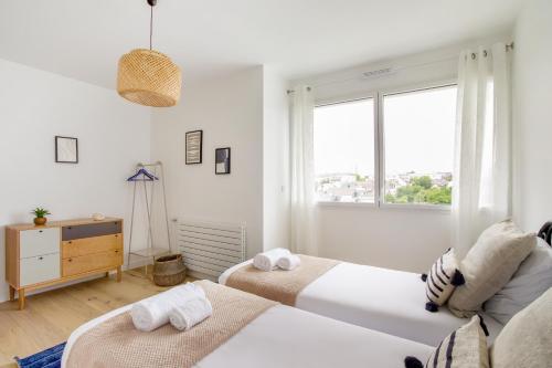 une chambre blanche avec deux lits et une fenêtre dans l'établissement L'Air - Elégant 2 chambres avec loggia dans résidence de haut standing, à Rennes