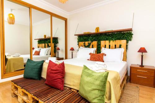 a bedroom with a large bed with colorful pillows at Apartamento Tocano Beach - By Dalma Portuguesa in Albufeira