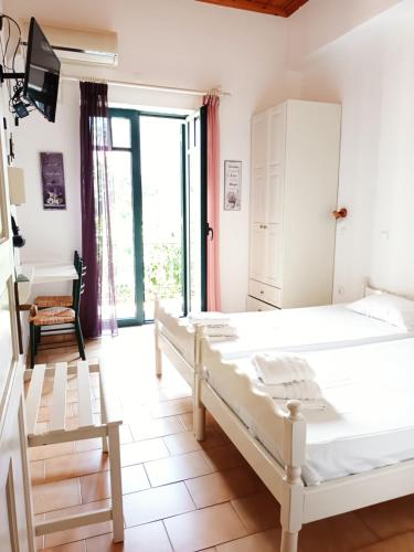 a bedroom with two beds and a tv on the wall at Skardamoula's Studios n Apartments in Kardamili