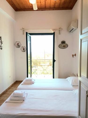 two beds in a room with a window at Skardamoula's Studios n Apartments in Kardamili