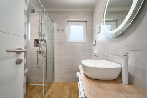 a white bathroom with a sink and a mirror at Apartmani Biserka in Mandre
