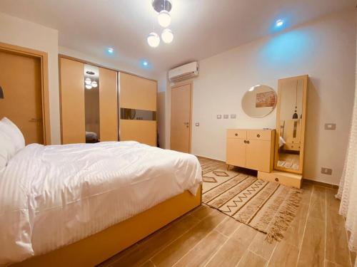 a bedroom with a white bed and a wooden floor at المونت جلاله - ll Monte Galala Ain Sokhna in Ain Sokhna