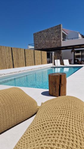 a pool with two chairs and a table next to a building at RASTONI VILLAS BY AEGEAN HOUSES in Psalidi
