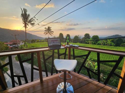 a laptop sitting on a wooden balcony with a chair at Taman Dari Villa in Sudaji