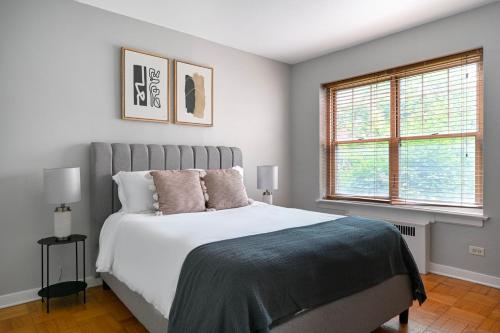 a bedroom with a large bed and two windows at Evanston 1br w courtyard wd nr beach CHI-955 in Evanston