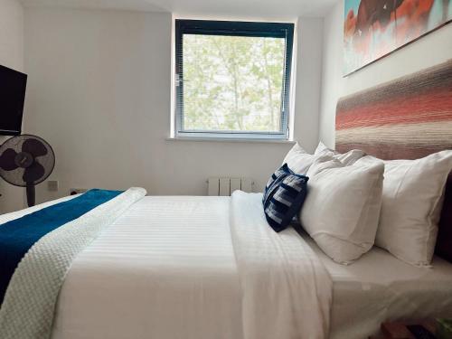 a bedroom with a white bed with pillows and a window at Canary Wharf - Luxury Apartments in London