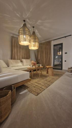 a living room with a bed and a table and chandeliers at RASTONI VILLAS BY AEGEAN HOUSES in Psalidi