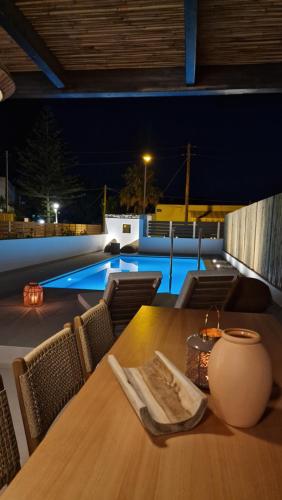 a table and chairs with a pool in the background at RASTONI VILLAS BY AEGEAN HOUSES in Psalidi