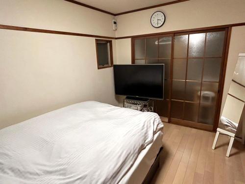 Schlafzimmer mit einem Bett und einem Flachbild-TV in der Unterkunft Casa Viento Stay Inn in Hiroshima