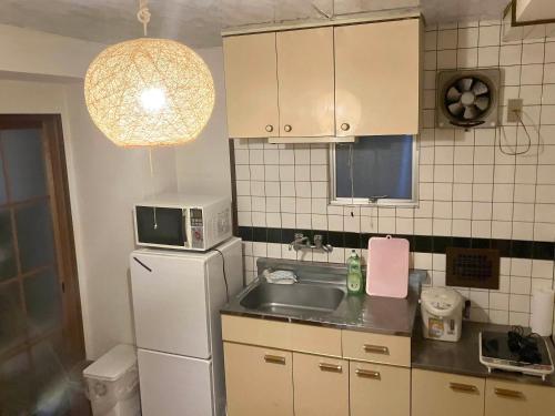 a kitchen with a white refrigerator and a sink at Casa Viento Stay Inn in Hiroshima