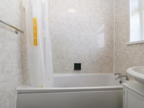 ein Badezimmer mit einer weißen Badewanne und einem Waschbecken in der Unterkunft Awelfryn in Holyhead