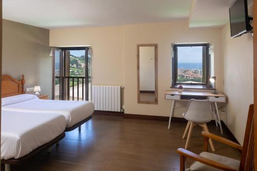a bedroom with a bed and a desk and two windows at Agroturismo Argoin Txiki in Zarautz